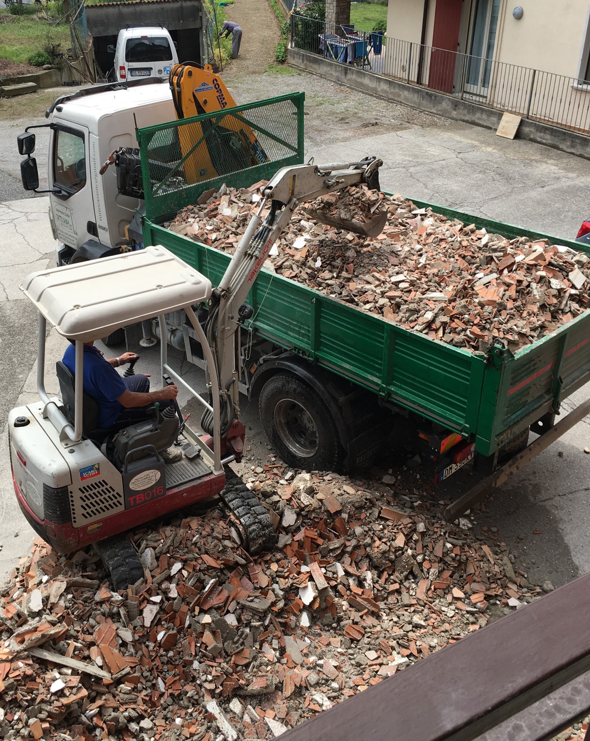 Furgone di impresa di costruzioni edile che raccoglie detriti da una demolizione residenziale a Brescia